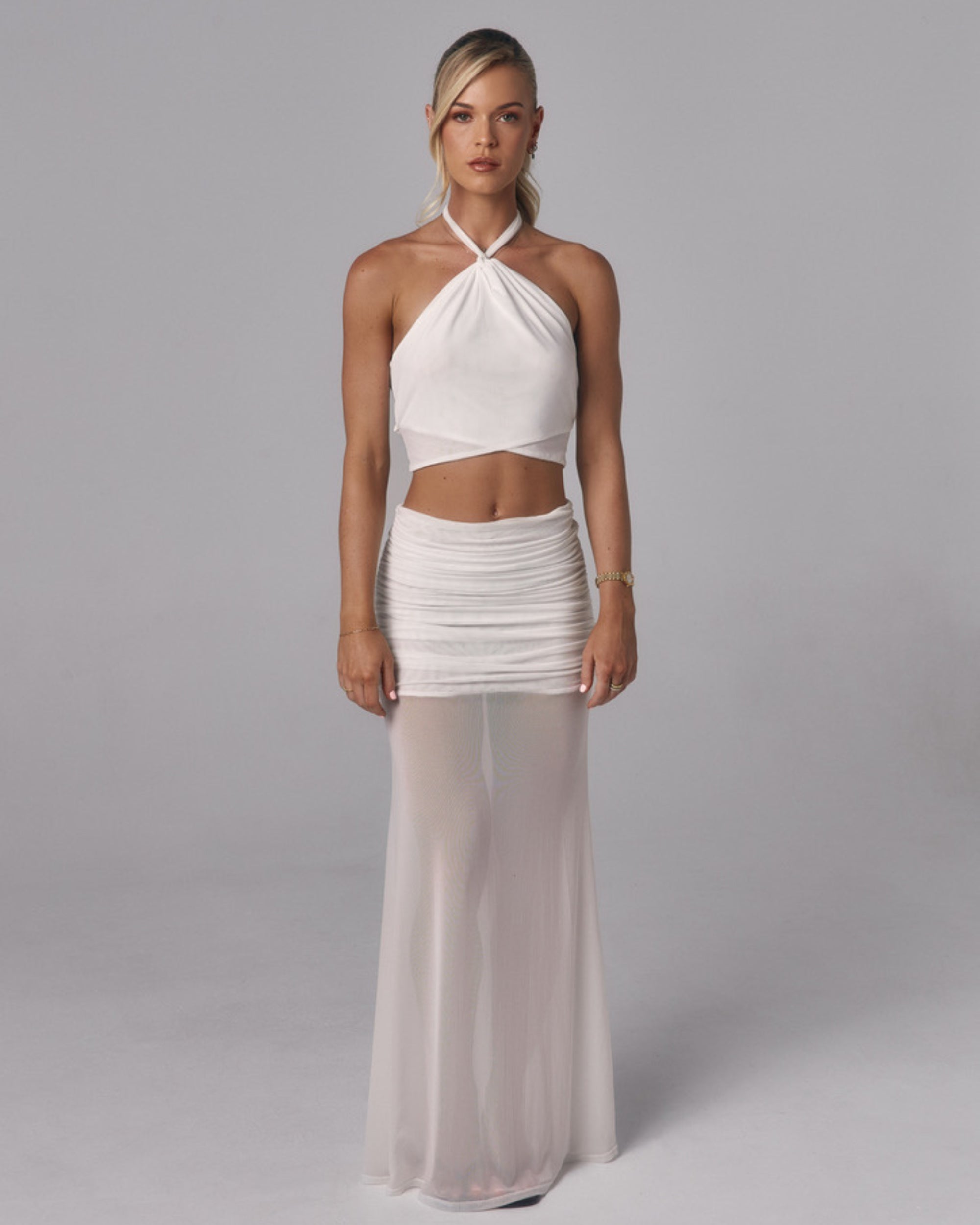 Front view of Elara ivory halter crop top with twisted neckline detail styled with the Elara sheer maxi skirt in studio.