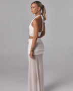 Side view of Elara ivory sheer maxi skirt with ruched mini lining styled with a white halter top in a studio setting.