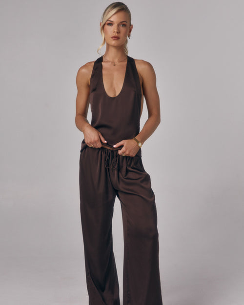 Model wearing Paloma chocolate brown satin lounge pants with matching satin top in a studio setting.