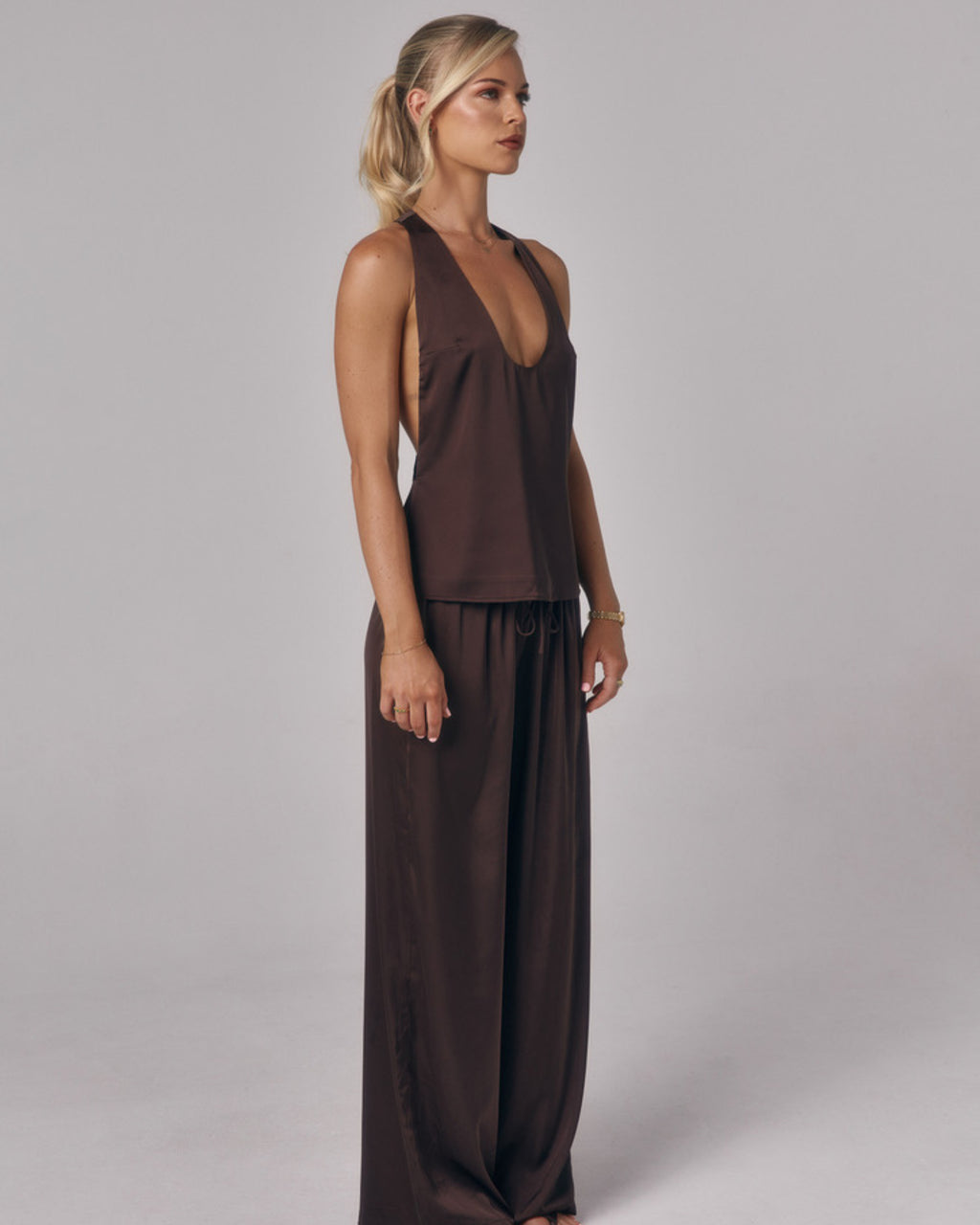 Side view of Paloma chocolate brown satin lounge pants with matching satin top in a studio setting.