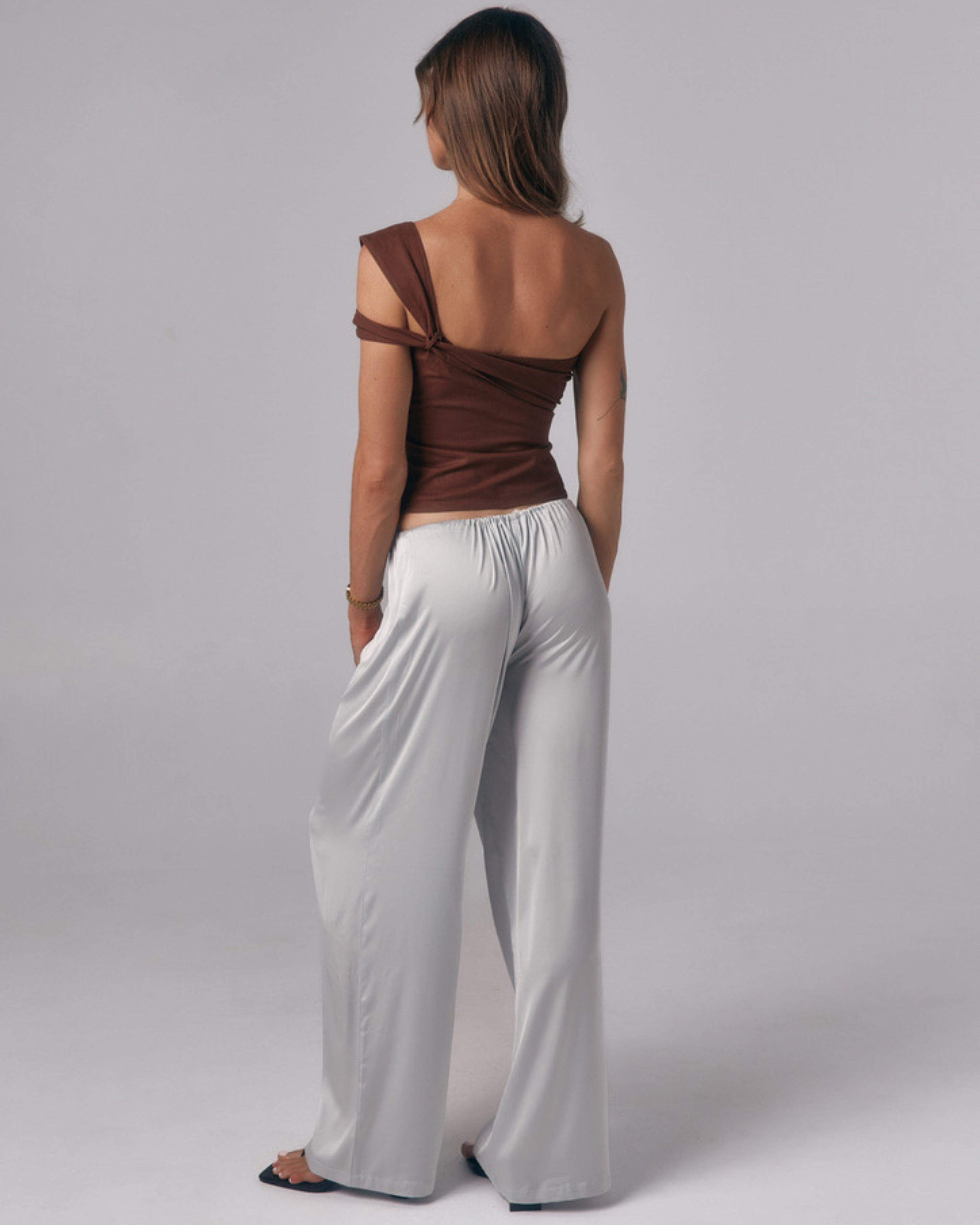 Back view of Paloma light blue satin lounge pants with wide leg fit in a studio setting.