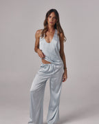 Model wearing Paloma light blue satin lounge pants with drawstring waist and wide leg fit in a studio setting.