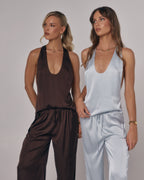 Models wearing Paloma satin lounge pants and matching tops in chocolate brown and light blue in a studio setting.